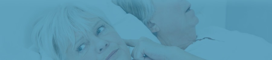 Elderly woman plugging her ears lying in bed